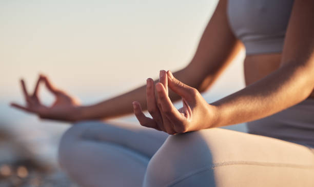 A person meditating peacefully on a yoga mat in a sunlit room.